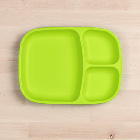 The Re-Play Divided Tray by REPLAY is a bright green plastic plate crafted from recycled material. It features three compartments—one large and two smaller ones—and sits on a light wooden surface. This eco-friendly divided tray provides both durability and sustainability for your tableware needs.