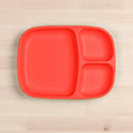 The REPLAY Re-Play Divided Tray is a square, red plastic tray crafted from recycled materials and features three compartments of varying sizes on a light wooden surface. This tray includes one large rectangular section, one medium oval section, and one smaller oval section—the perfect option for durable tableware.