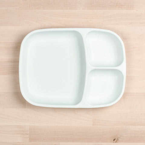 A REPLAY Re-Play Divided Tray, crafted from recycled white plastic and featuring three compartments, is placed on a light wooden surface. The tray includes a larger section on the left and two smaller sections on the right, offering an eco-friendly and practical solution for your durable tableware needs.