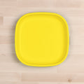 A square-shaped Re-Play Large Flat Plate by REPLAY, featuring a bright yellow hue and rounded edges, made in America, is placed on a light wood surface. The clean, minimalistic design and vibrant color contrast beautifully with the neutral background.