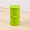 The REPLAY Re-Play Snack Stack is a lime green, cylindrical container featuring a textured lid and base, crafted from recycled material. Its innovative design includes a narrower central section and ring-like grooves around the top, middle, and bottom areas. This eco-friendly addition to your sustainable tableware collection is showcased on a light wood surface with a white tiled backsplash.