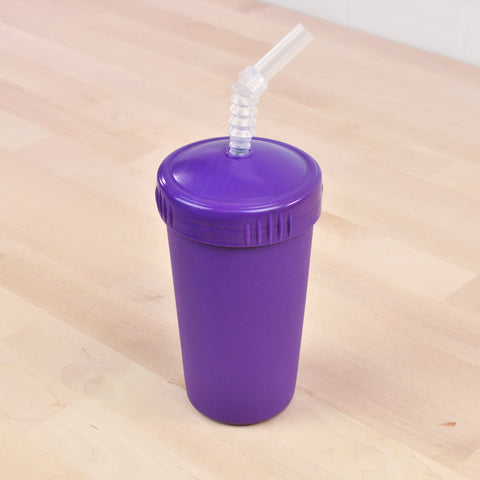 The Re-Play Straw Cup by REPLAY, featuring a purple plastic design with a matching lid and flexible clear straw, is placed on a wooden surface. Made in the USA, this sustainable cup boasts a textured finish, while the lid includes indentations for easy grip. The slightly bent clear straw extends out from the top center of the lid.