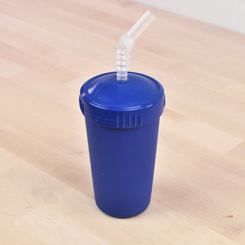 A Re-Play Straw Cup from REPLAY, featuring a matching blue lid and a flexible, transparent straw, stands on a light wooden surface. The straw curves in a zigzag pattern near the top and is inserted through a hole in the lid. Made in the USA, this sustainable plastic tumbler is both stylish and eco-friendly.