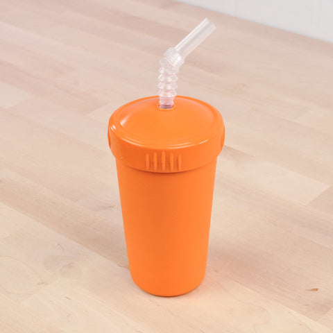 A Re-Play Straw Cup from REPLAY, made of orange plastic and accompanied by a matching lid and flexible recycled straw, is placed on a light wooden surface.