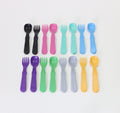 The Re-Play Utensil Set by REPLAY features an assortment of colorful toddler utensils made from recycled plastic, each combining a spoon on one end and a fork on the other. These dishwasher-safe utensils are arranged in three rows and come in colors such as black, dark purple, pink, teal, light blue, light purple, green, gray, and yellow.